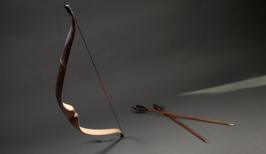 Bild auf dem ein Bogen und mehrere Pfeile in einem grauen Raum zu sehen sind
